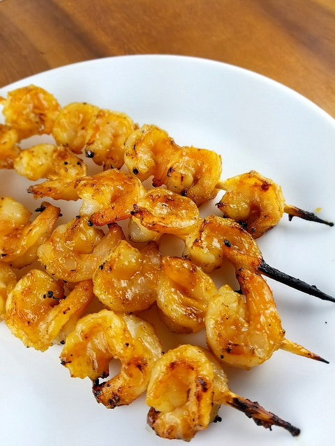 kewers of teriyaki grilled shrimp served on a white plat