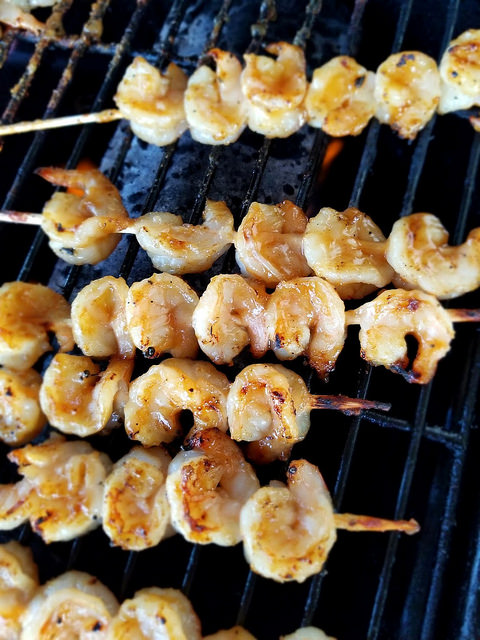 Skewers of teriyaki grilled shrimp cooking over a grill