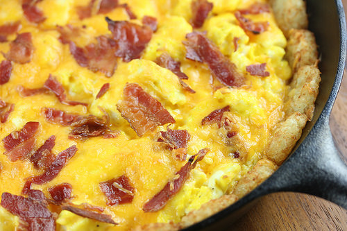 Close-up of tater tot breakfast pizza showing crispy bacon and melted cheddar over eggs