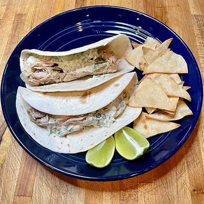 Top view of pork verde tacos on blue plate.