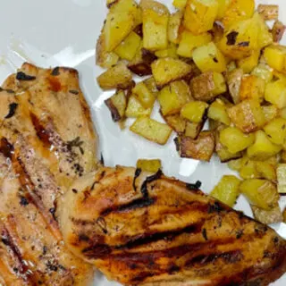Top view of artisan grilled chicken on plate with potatoes.
