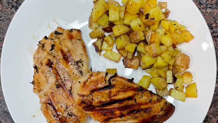 Top view of artisan grilled chicken on plate with potatoes.