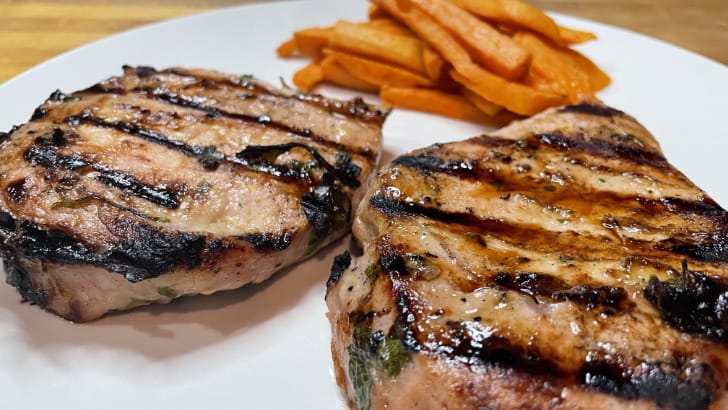 Grilled Cuban pork chops, plated with sweet potato fries.