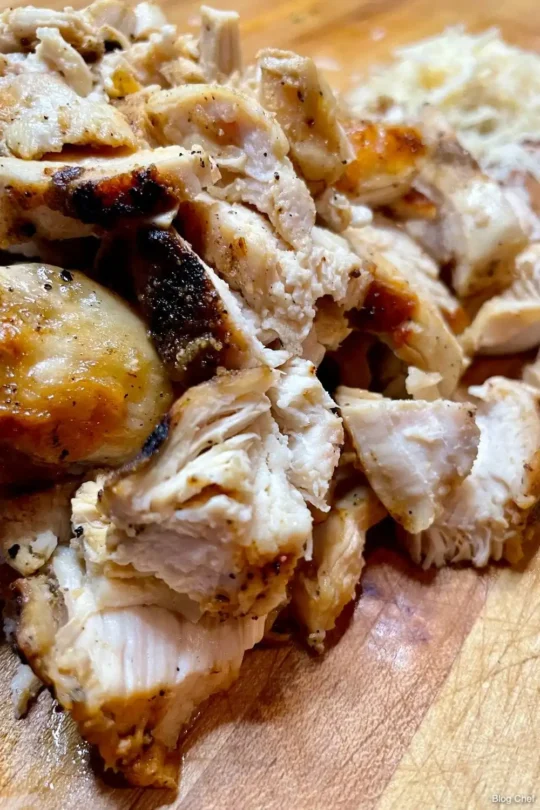 Close up of grilled, sliced chicken on cutting board.