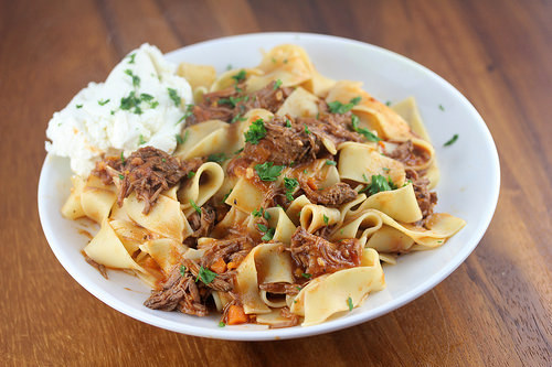 Plate of pappardelle pasta topped with short rib ragu and fresh parsley