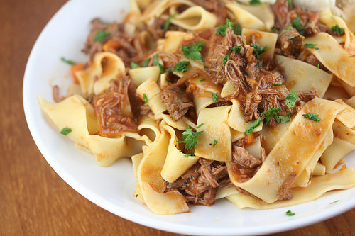 Plate of pappardelle pasta topped with short rib ragu and fresh parsley