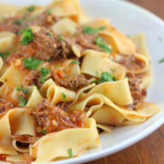 Plate of pappardelle pasta topped with short rib ragu and fresh parsley