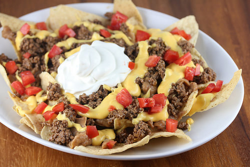 Nachos Bell Grande topped with ground beef cheese tomatoes and sour cream