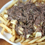 Plate of French fries topped with shredded short ribs and melted cheese curds