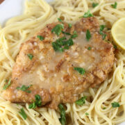 French chicken with lemon butter sauce served over pasta and garnished with parsley