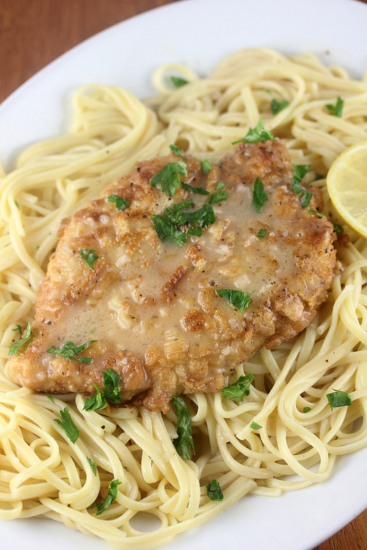 French chicken with lemon butter sauce served over pasta and garnished with parsley