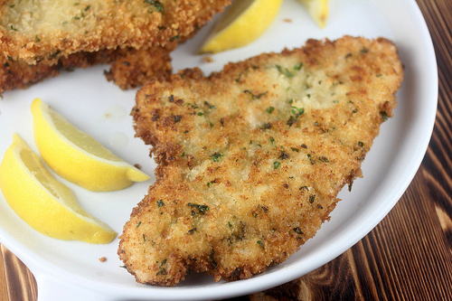 German chicken schnitzel served with lemon wedges on a white plate