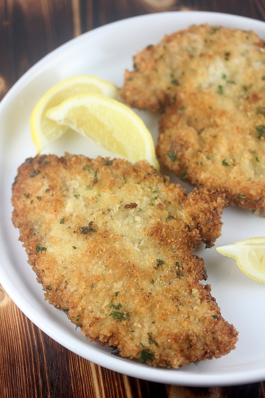 German chicken schnitzel served with lemon wedges on a white plate