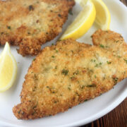 German chicken schnitzel served with lemon wedges on a white plate