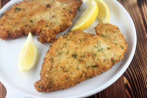 German chicken schnitzel served with lemon wedges on a white plate