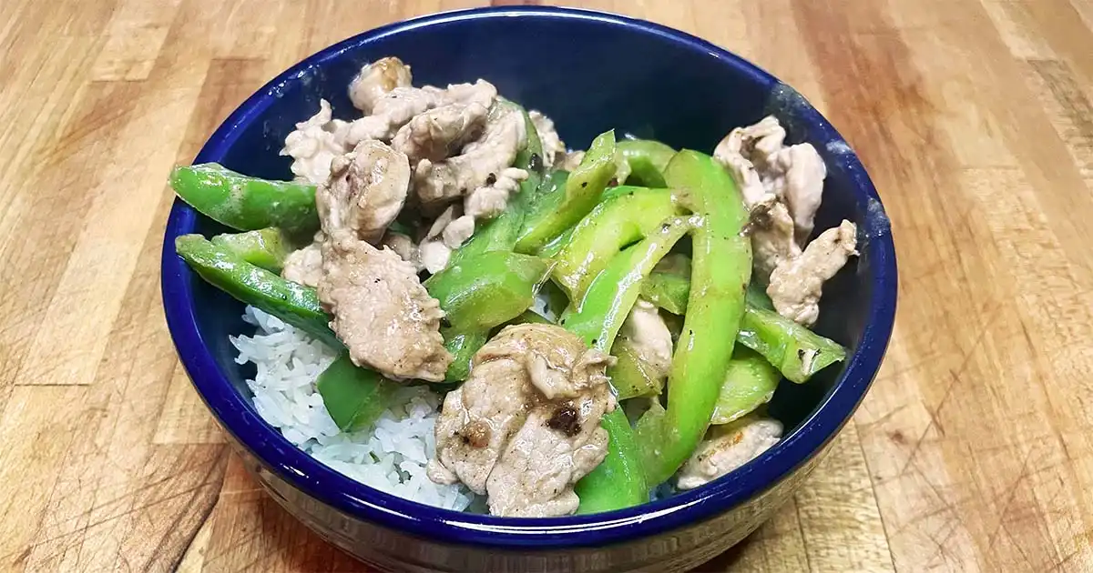 Prepared pork and pepper stir fry over white rice.