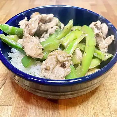 Prepared pork and pepper stir fry over white rice.