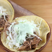Corn tortilla topped with shredded pork, shredded cabbage, and creamy green sauce