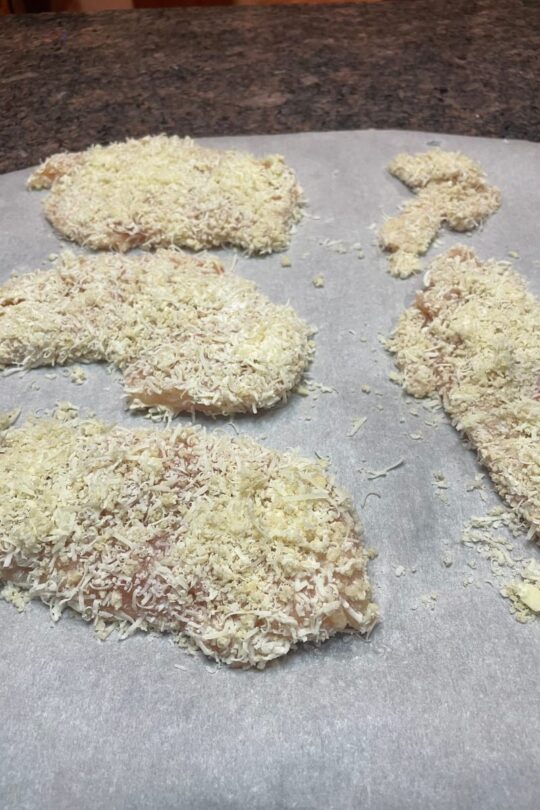 Breaded chicken breasts on parchment paper.