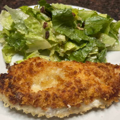 Chicken Romano prepared on plate with salad.