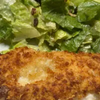 Chicken Romano prepared on plate with salad.