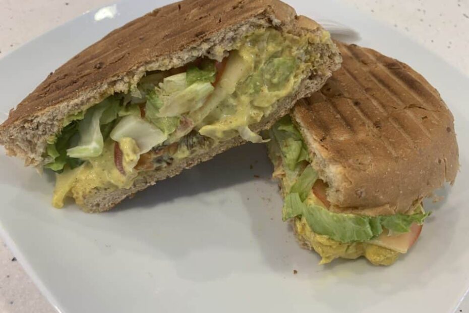 Coronation chicken salad sandwich cut in half and served on a white plate
