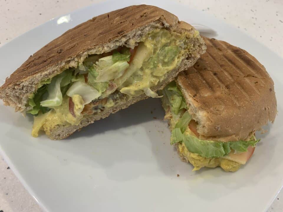 Coronation chicken salad sandwich cut in half and served on a white plate