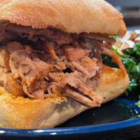 Close up view of oven-roasted pulled pork served on ciabatta roll.