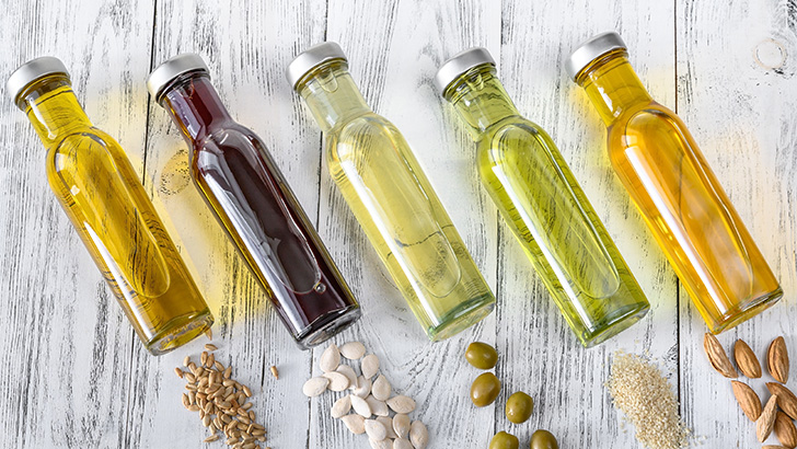 Various vegetable oils including olive oil lined up on table.