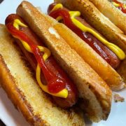 Stovetop hotdogs in buns with ketchup and mustard.