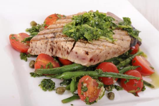 Oven-baked tuna steaks served over green beans and tomatoes