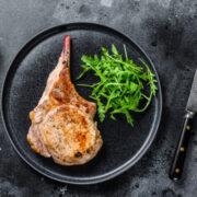 Prepared, bone-in pork chop on plate.