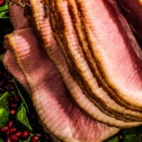 Top view of spiral cut ham on top of spinach and pomegranate seeds.