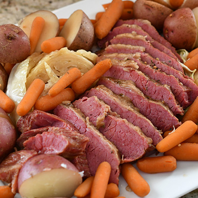 Close up of slow cooker corned beef with carrots, potatoes, and cabbage.