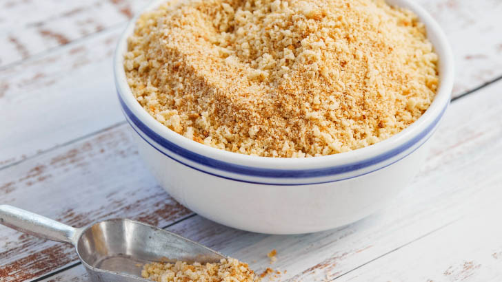 Bowl of bread crumbs on table. 