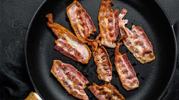 Overhead view of cooked bacon strips in skillet.