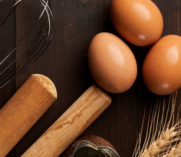 Eggs and wheat on dark surface.
