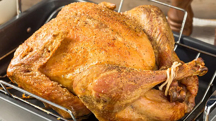 Seasoned turkey cooked in the oven in a roasting pan.