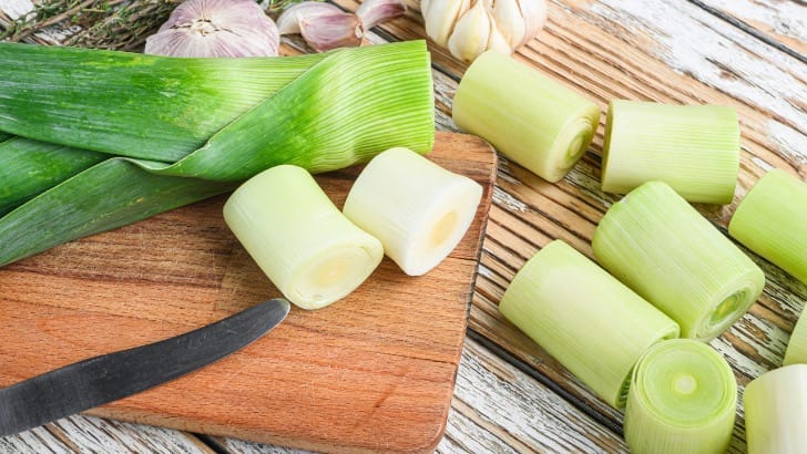 Fresh, raw leek sliced into chunks on cutting board.