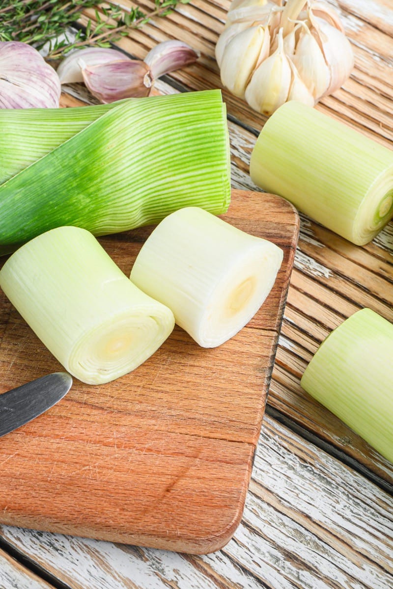 Fresh, raw leek sliced into chunks on cutting board.