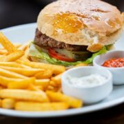 prepared hamburger on plate with fries and sauces