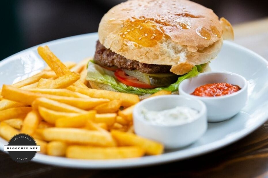 prepared hamburger on plate with fries and sauces