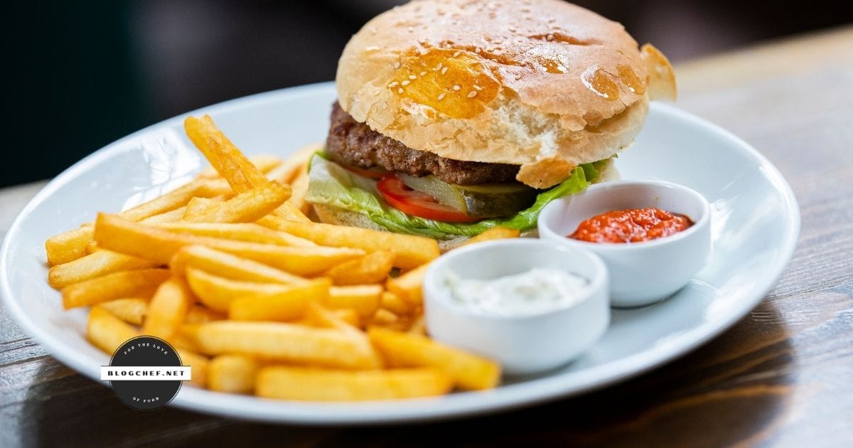 prepared hamburger on plate with fries and sauces