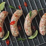 Four Italian sausages cooking on the grill.
