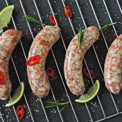 Four Italian sausages cooking on the grill.