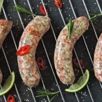 Four Italian sausages cooking on the grill.