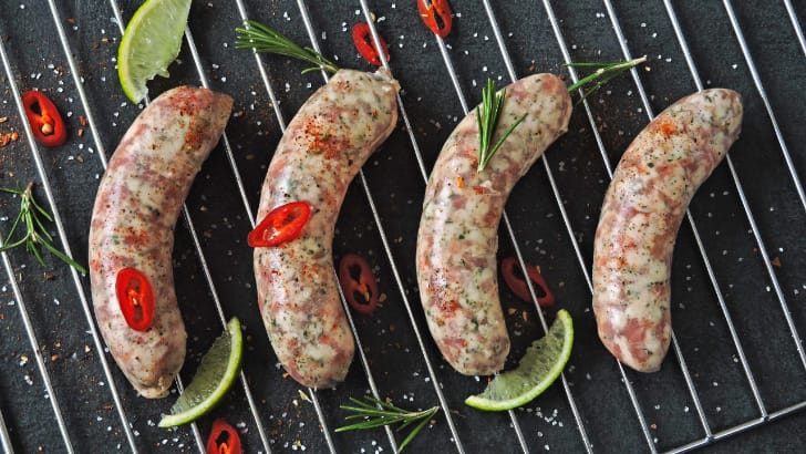 Four Italian sausages cooking on the grill.