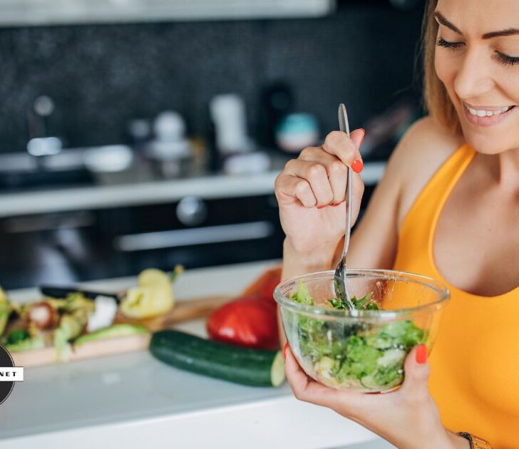 Woman eats salad while smiling.