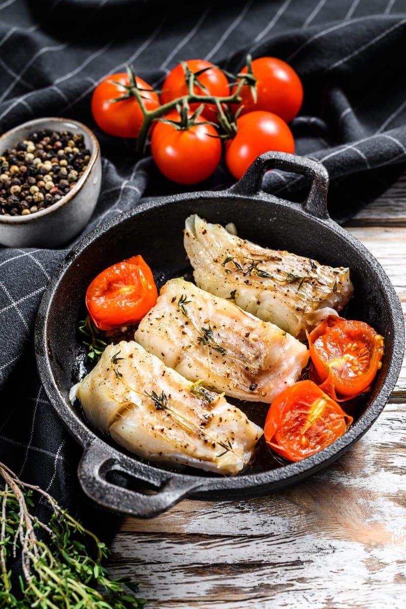 Overhead view of codfish cooked in a pan.