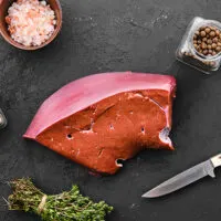 Raw beef liver on surface with spices.